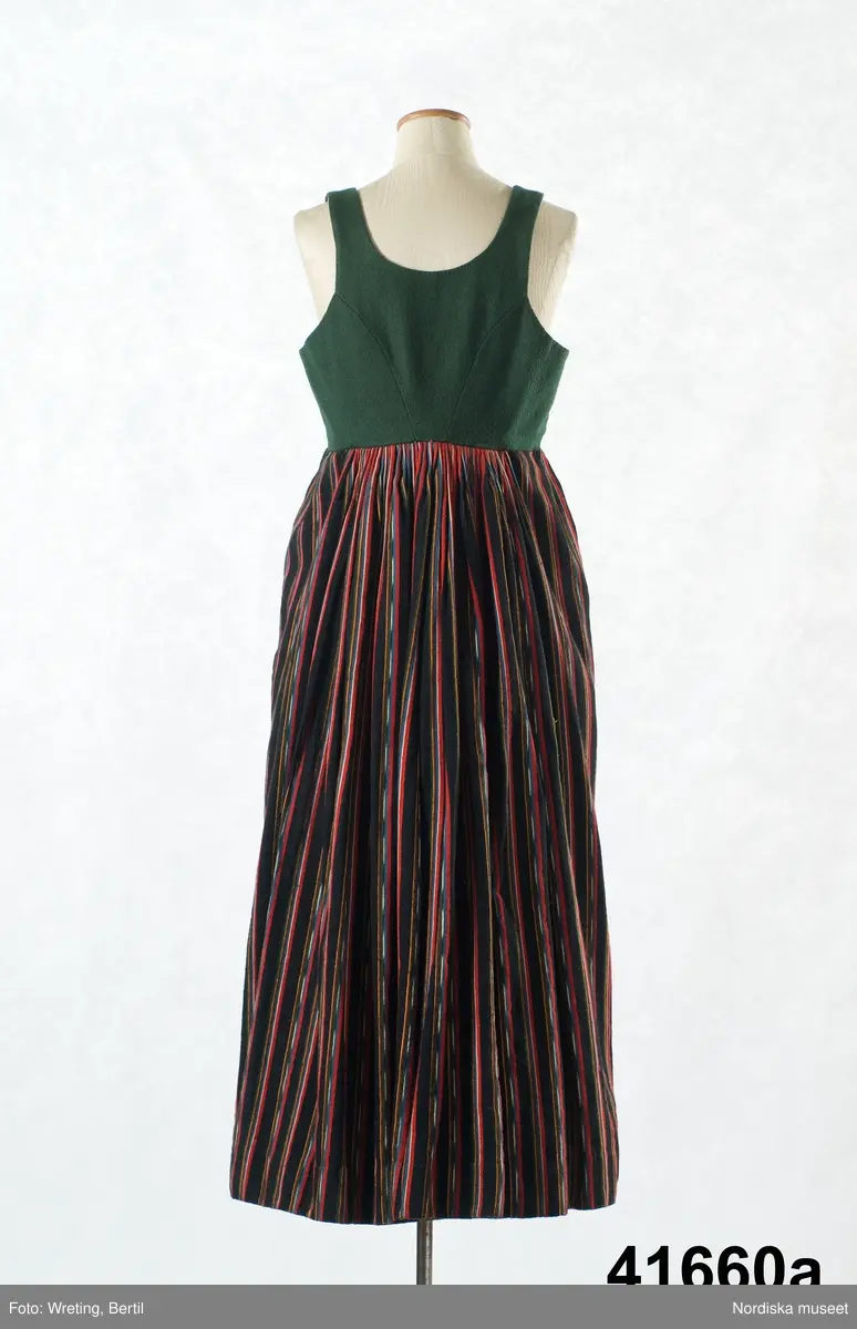 a. Livstyckskjol med liv av grön vadmal och randig halvyllekjol
b.Kvinnotröja, kort modell av svart kläde, med litet skört.
c. Halskläde av rödbottnad kattun
d. Halskläde av röd/gulrutig bomullslärft
e. Kjolväska  av svart kläde med applikationer av vadmal med tenntrådskonturer.
g: 1-4,  mjuk bindmössa av ljusblå sidenbrokad med vita spetsbandsmönster samt blommönster i rosa, mörkrött, vitt och grönt mm.

Dräktdelarna förefaller att vara från något olika tider, och sammansatta för att bli en hel dräkt vid insamlandet till museet. För att illustrera ett äldre dräktskick på orten. 
/Berit Eldvik 2012-02-14