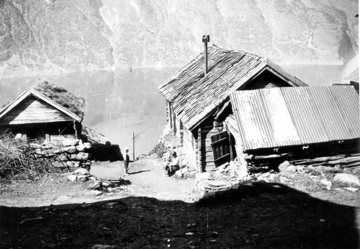 Liten gutt og kvinne med barn på fanget ved bebyggelse i Aurlandsdalen.