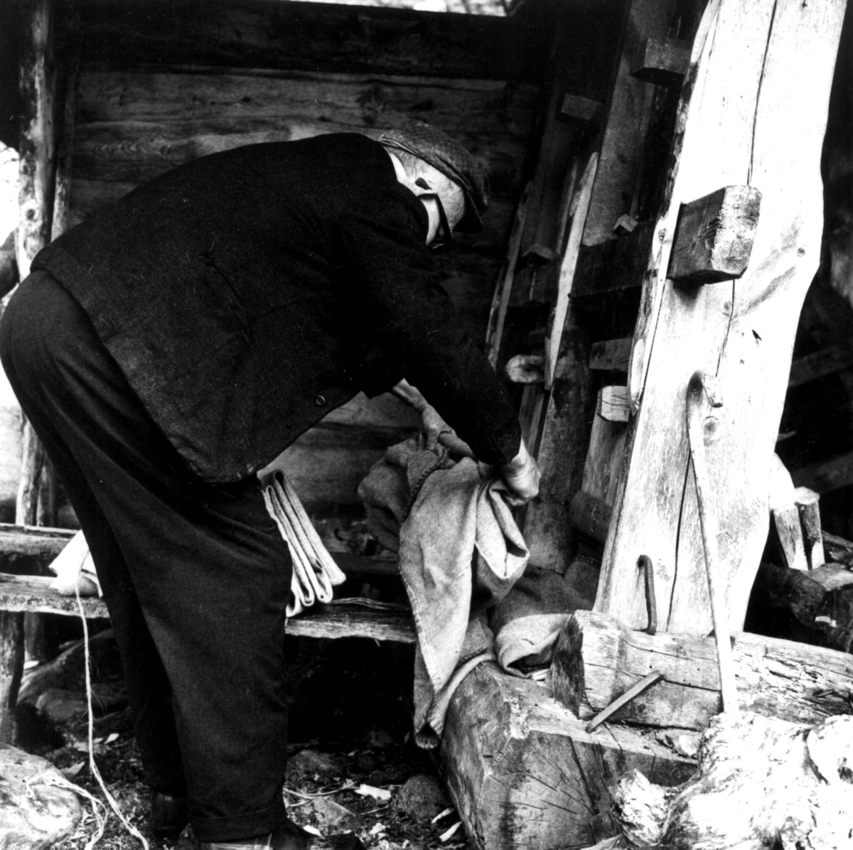 Stamping av vadmel. Ingemund Kvæstad legger vadmel i kupene i stampa. Kvæstad, Suldal, Rogaland 1970.