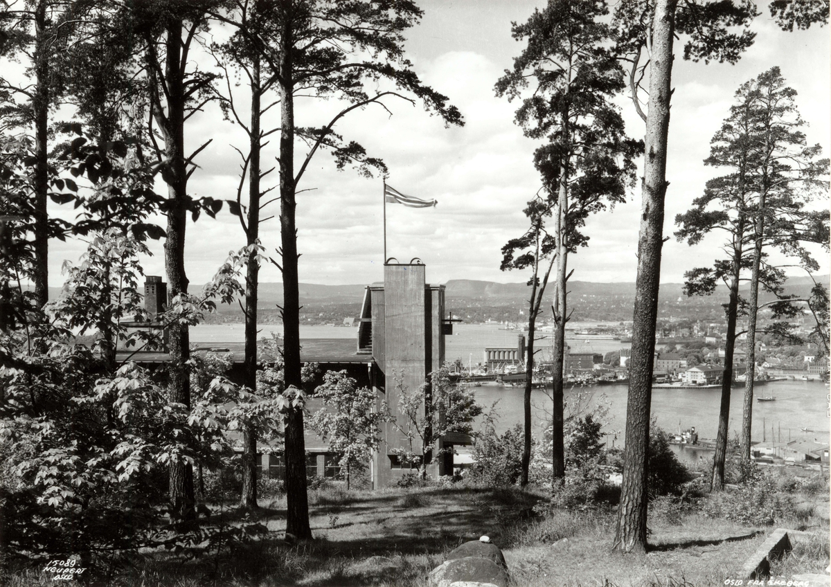 Ekeberg, Oslo 1937. Utsikt gjennom trærne til restauranten og mot Oslo havn og byen. Vimpel
på restauranten.