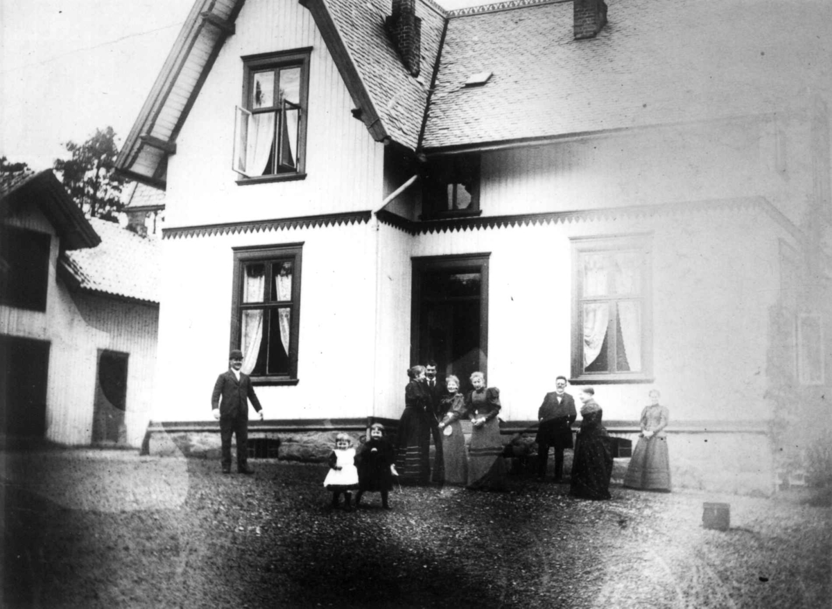 Granbakken, Asker, Akershus. Gruppe mennesker på gårdsplass foran hus og uthus.