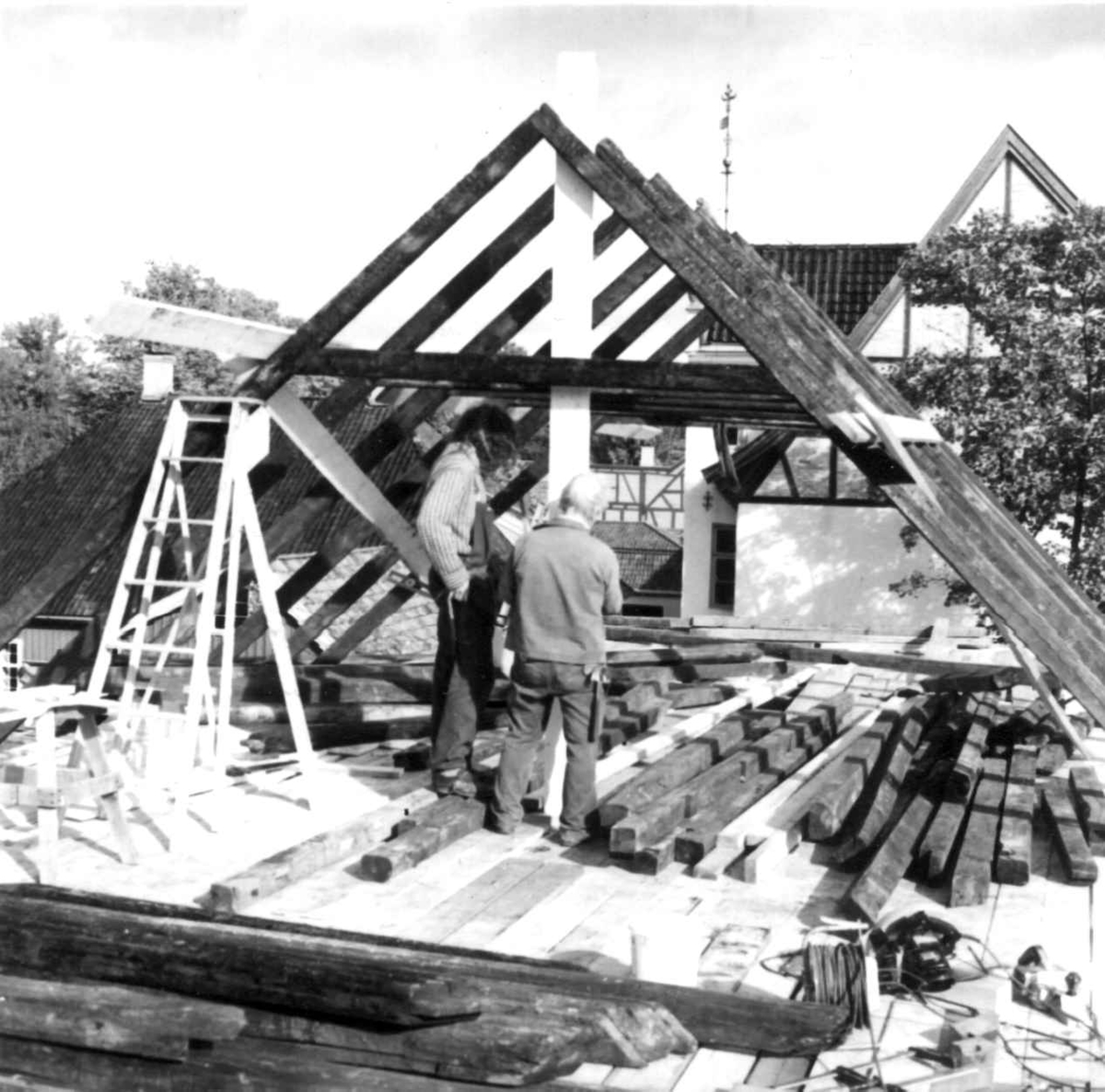 Byggmester John Folland og snekkerlærling Ivar Jørstad i arbeid med reisverket til lagerbygning fra Vaterland, under oppføring på Norsk Folkemuseum i 1979.