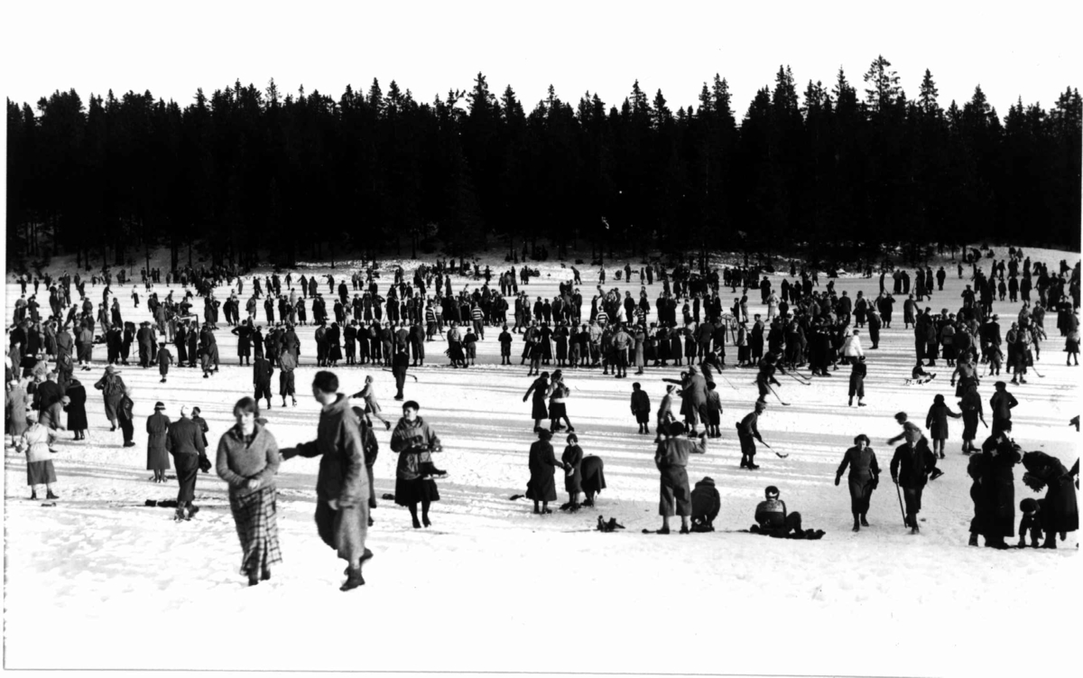 Tryvann Skøytestadion, Oslo, 1934. Skøyteløpere i aksjon på isen. Noen med bandykølle.