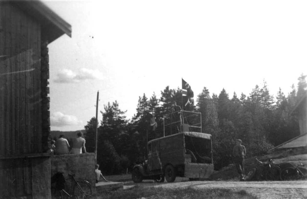 "Nasjonal Samling". En mann ved en lastebil og to kvinner og en gutt som sitter på trappen til et hus. Gjøvdal 1936.