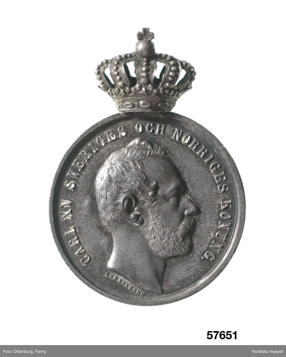 Huvudliggaren:
"Utmärkelsetecken. På åtsidan: 'FÖR ÖMSINT VÅRD OM VÄRNLÖSA BARN'. På frånsidan: 'CARL XV SVERIGES OCH NORIGES KONUNG', 'LEA AHLBORN'.
Ink.hos juden S. C. Dunér i Stockholm jämte 57.650-57.658 för [...]. Ankom 3/9 1888."