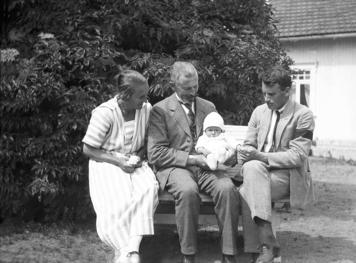 Eyvind Arenzt sitter sammen med sønnen Thorleif Arenzt og svigerinnen Liv Arentz og sitt barnebarn Eivind Arentz på en benk i en hage.