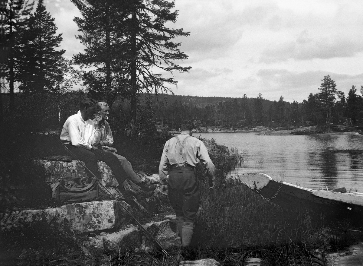 Tre menn sitter med fiskeutstyr og robåt ved Mykle, Buskerud.