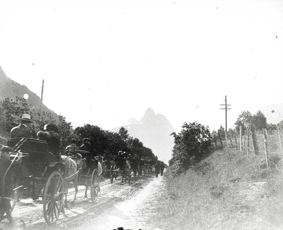 Romsdalen mot Romsdalshorn, Møre og Romsdal. Rekke av heste kjerrer på vei.