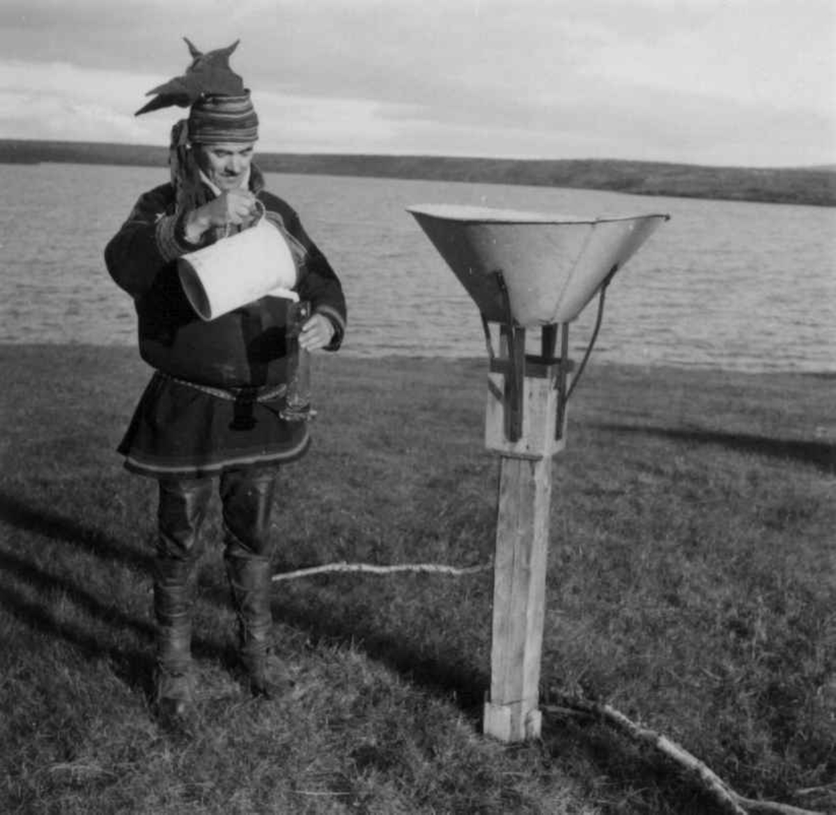 Elias Øvergård står ved siden av et måleinstrument for måling av  nedbørsmengden. Siccajavri, Kautokeino.