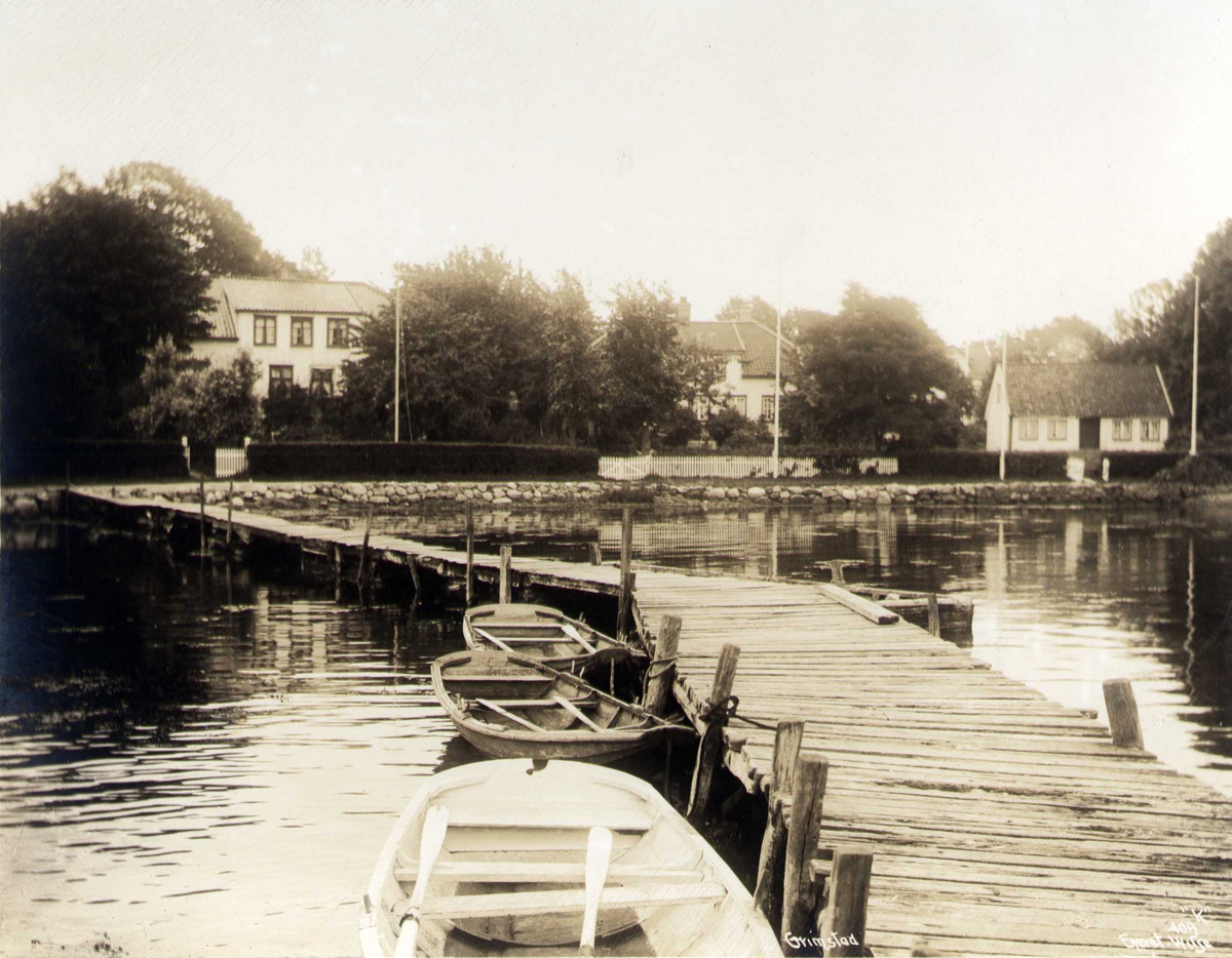 Bolighus ved sjøen, Grimstad, Aust-Agder. Brygge med robåter i forgrunnen.