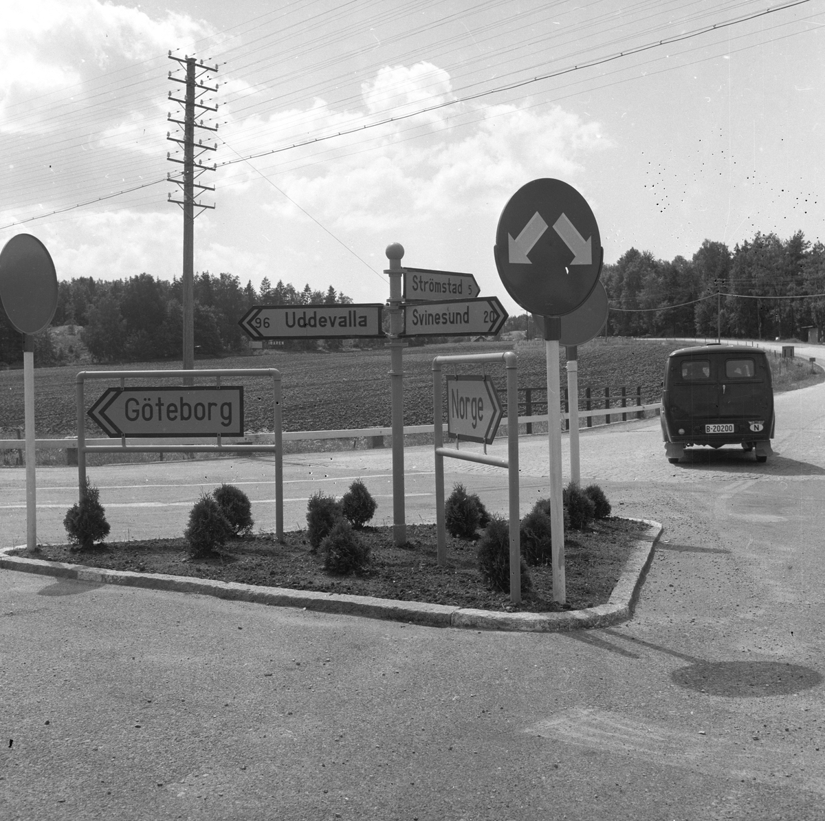 Langs Riksvei 1 i Sverige, står det en trafikkøy med skilt som henviser til Norge, Strømstad, Göteborg etc. Fotografert 7. juli 1958.