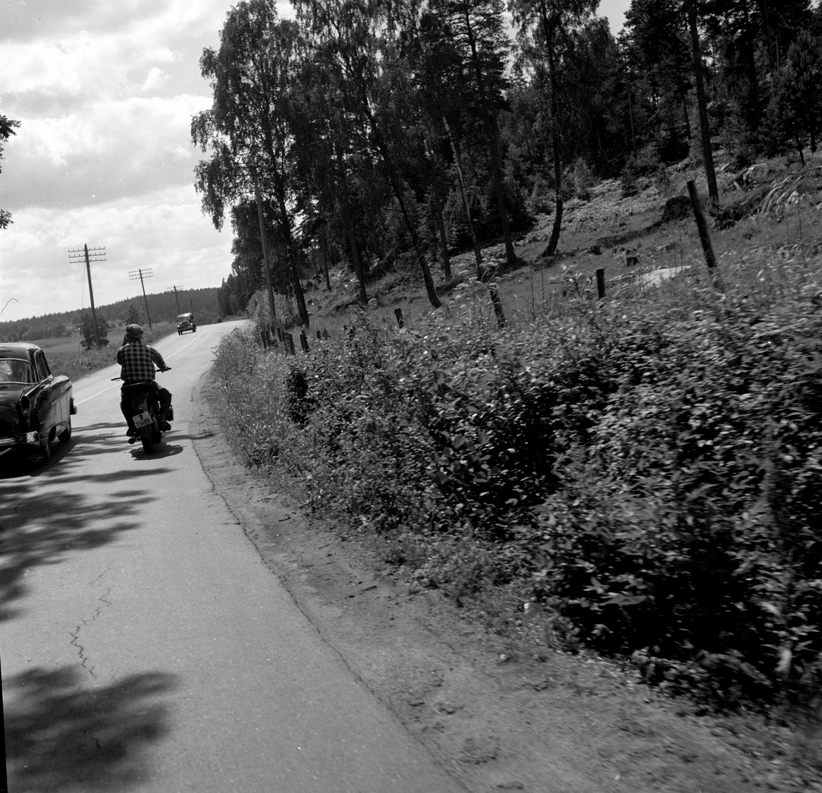 Langs Riksvei 1 kjører en bil forbi en motorsykkel. Fotografert 7. juli 1958.