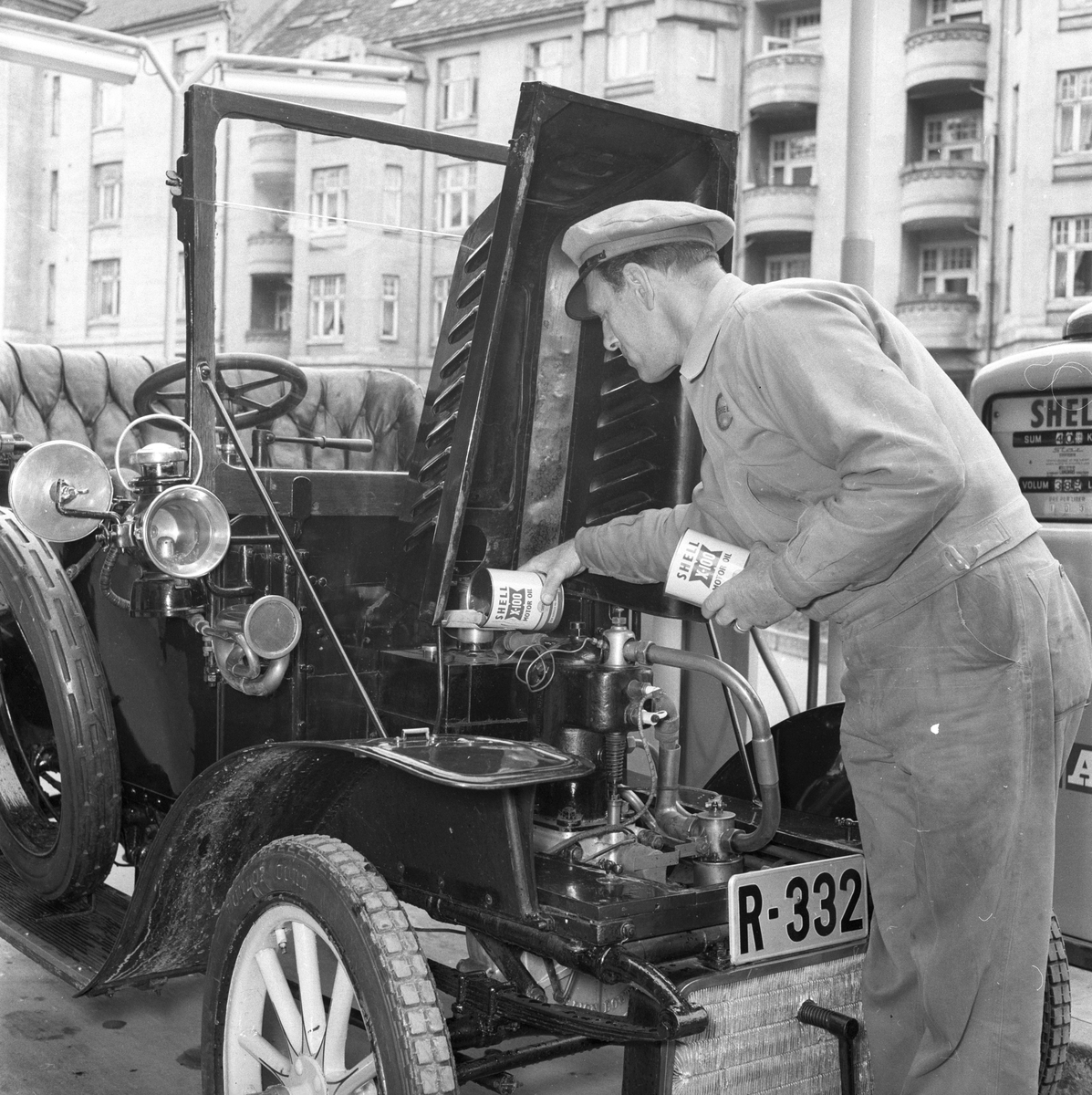 Bensinstasjonsbetjent fyller olje, Shell X-100 motor oil, på veteranbil De Dion Bouton, Motor. Fotografert ant 1964.