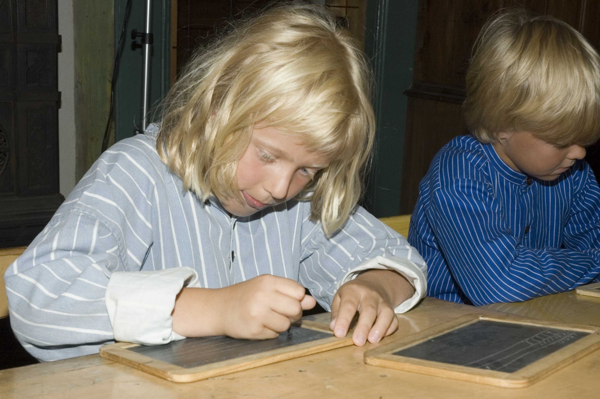 Levendegjøring på museum.
Ferieskolen uke 31. Elev skriver på travlen.
Norsk Folkemuseum, Bygdøy.