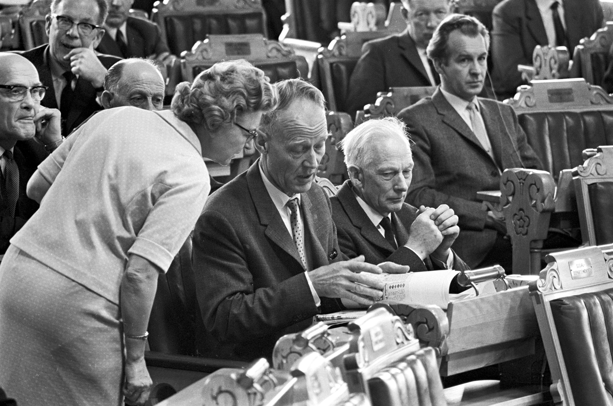 Serie. Debatt i Stortinget. Kåre Willoch og John Lyng leser dokumenter og en kvinne snakker med en politiker. Fotografert våren 1967.