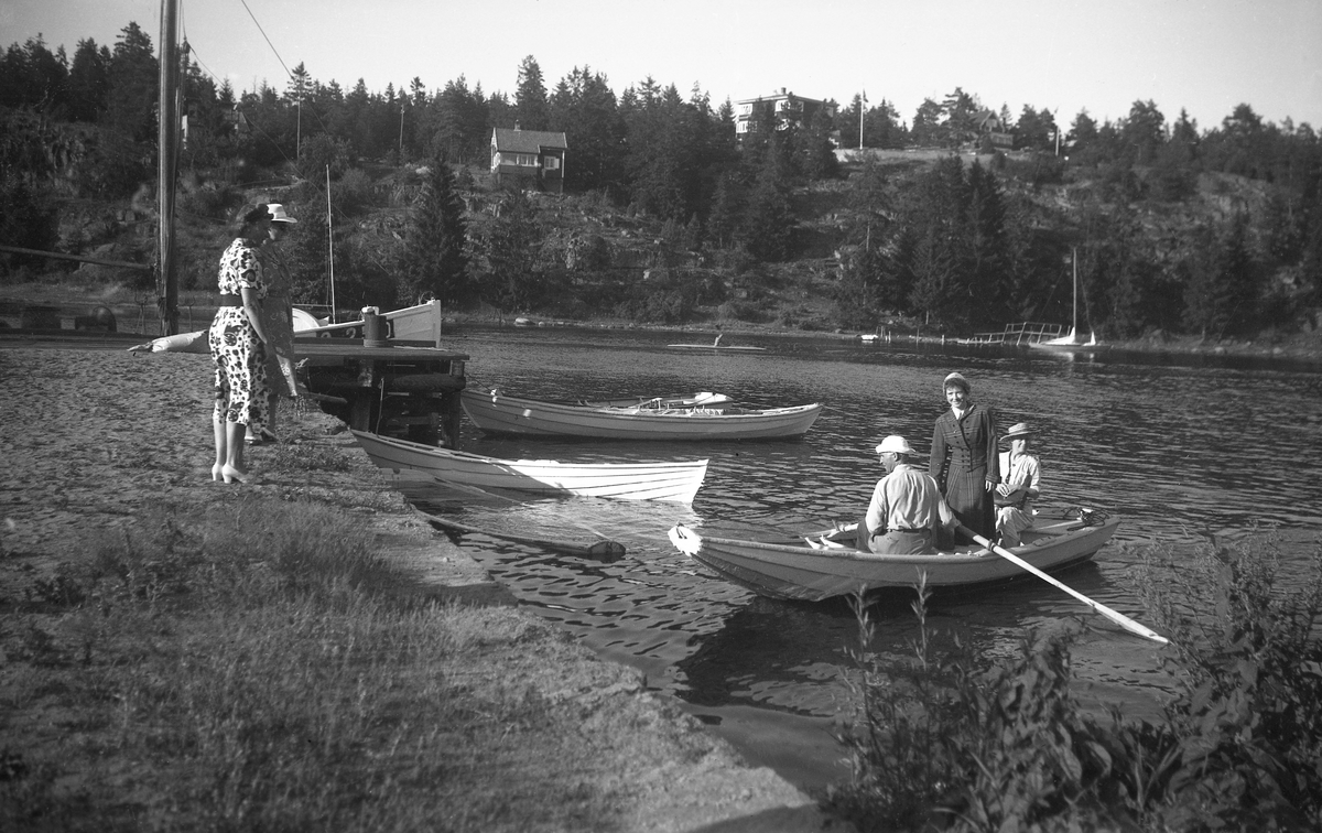 To kvinner tar imot en robåt med to kvinner og en mann på Nesbrygga på Nøtterøy. Fotografert høsten 1948.