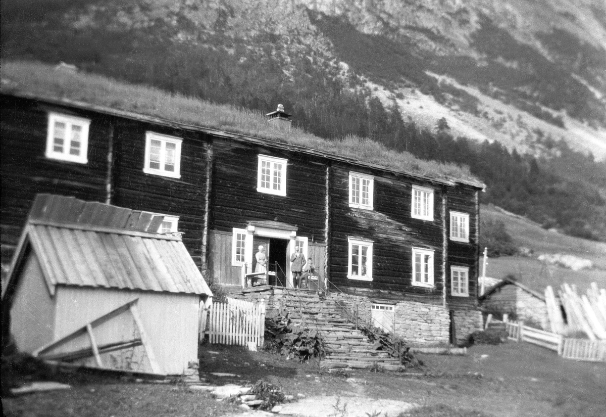 Våningshus på Stenboeng i Storlidalen, Oppdal. Fotografert ca. 1925. Kvinne, mann og barn skimtes på topppen av trappen.