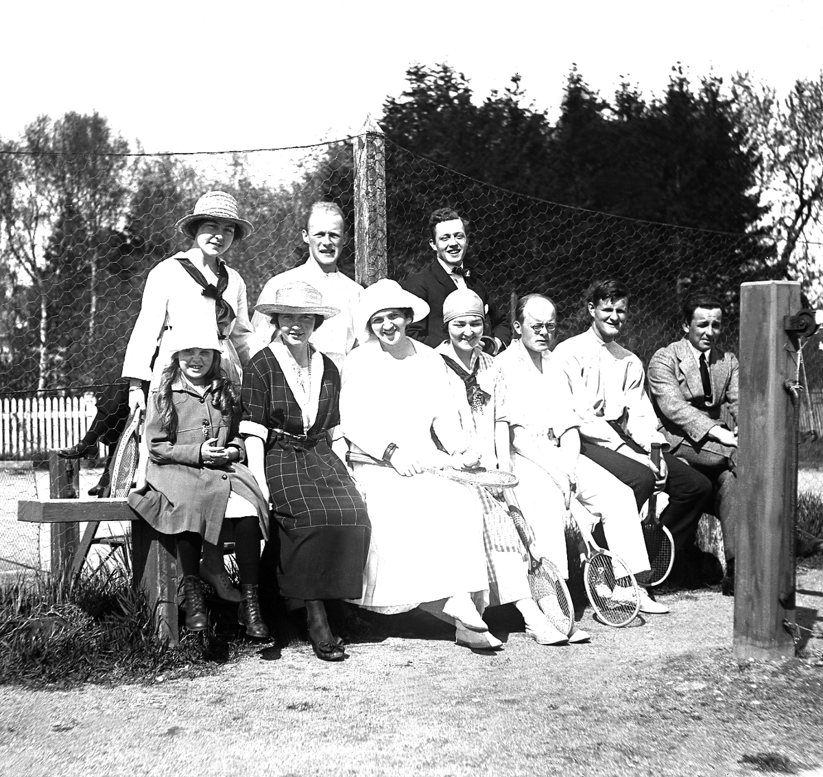 Gruppe av kvinner, menn og en jente på tennisbane i Trondheim. Fotografert 1920.