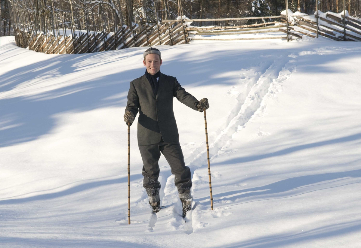 En serie med bilder av utkledd mann i klær anno 1870-1900 som går på ski på jordet bak festplassen.
Illustrasjonsfotografier.