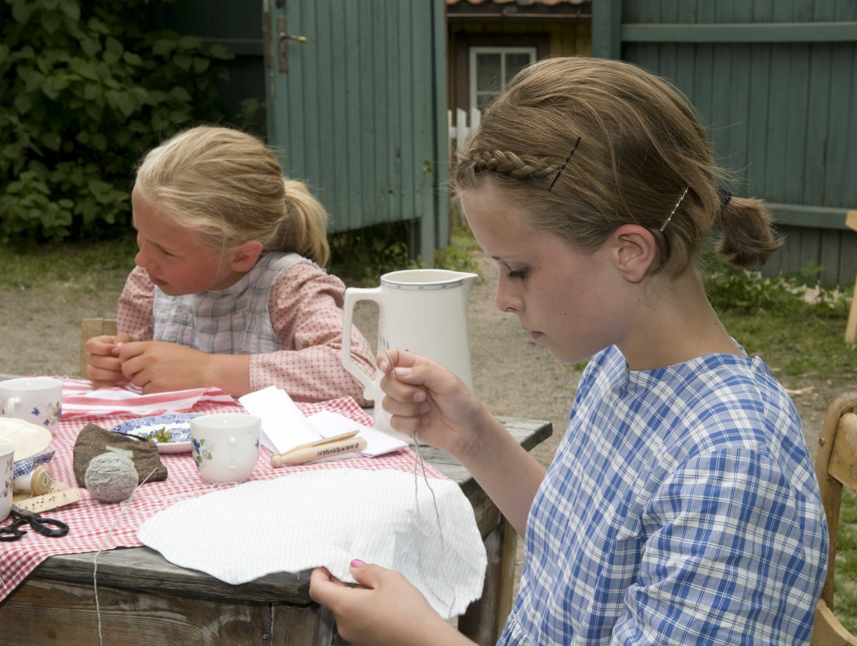 Ferieskolen uke 27, 2009.
Jenter på Enerhaugen syr poser til å ha stikker i.
