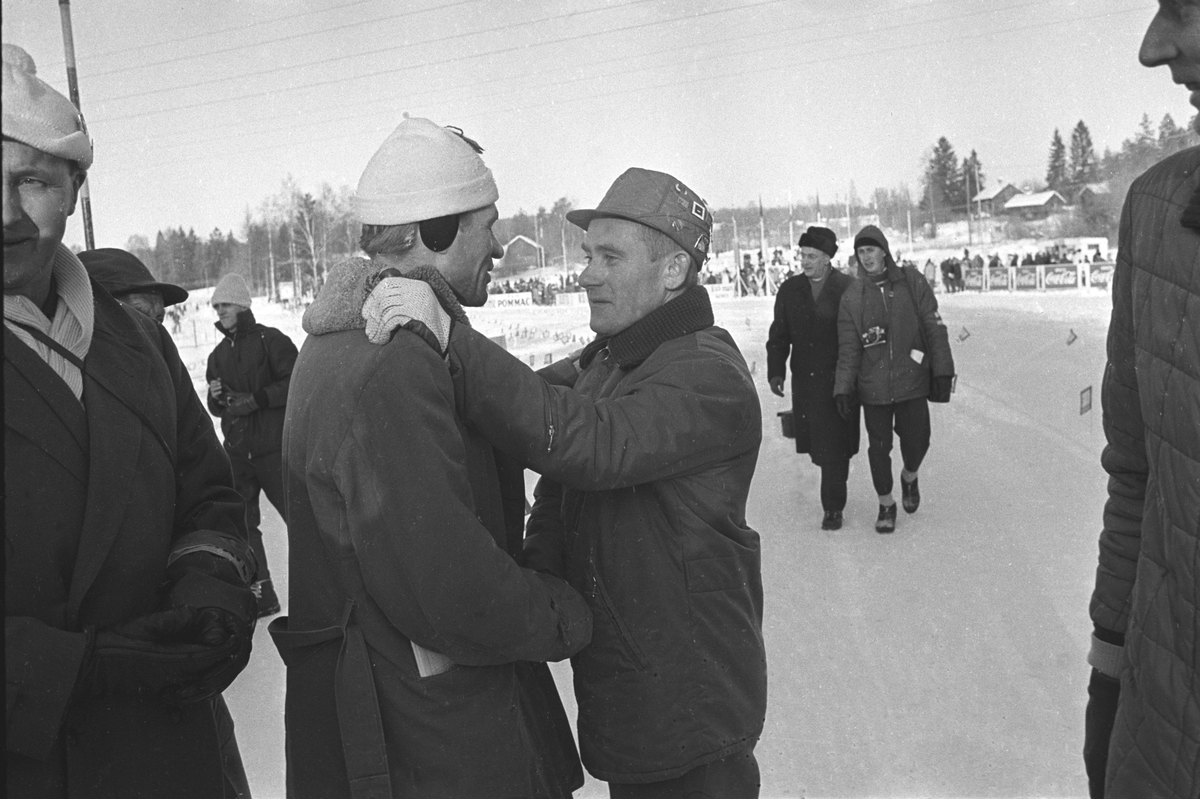 Finsk skiløper i midten blir gratulert i målområdet. Svenska Skispelen i Falun i 1967.