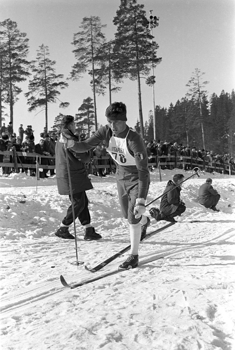 Skiløper med startnummer 78 i Holmenkollen. Publikum langs løypa.  Pressefotografer på sidelinjen. Holmenkollrennene 1963.