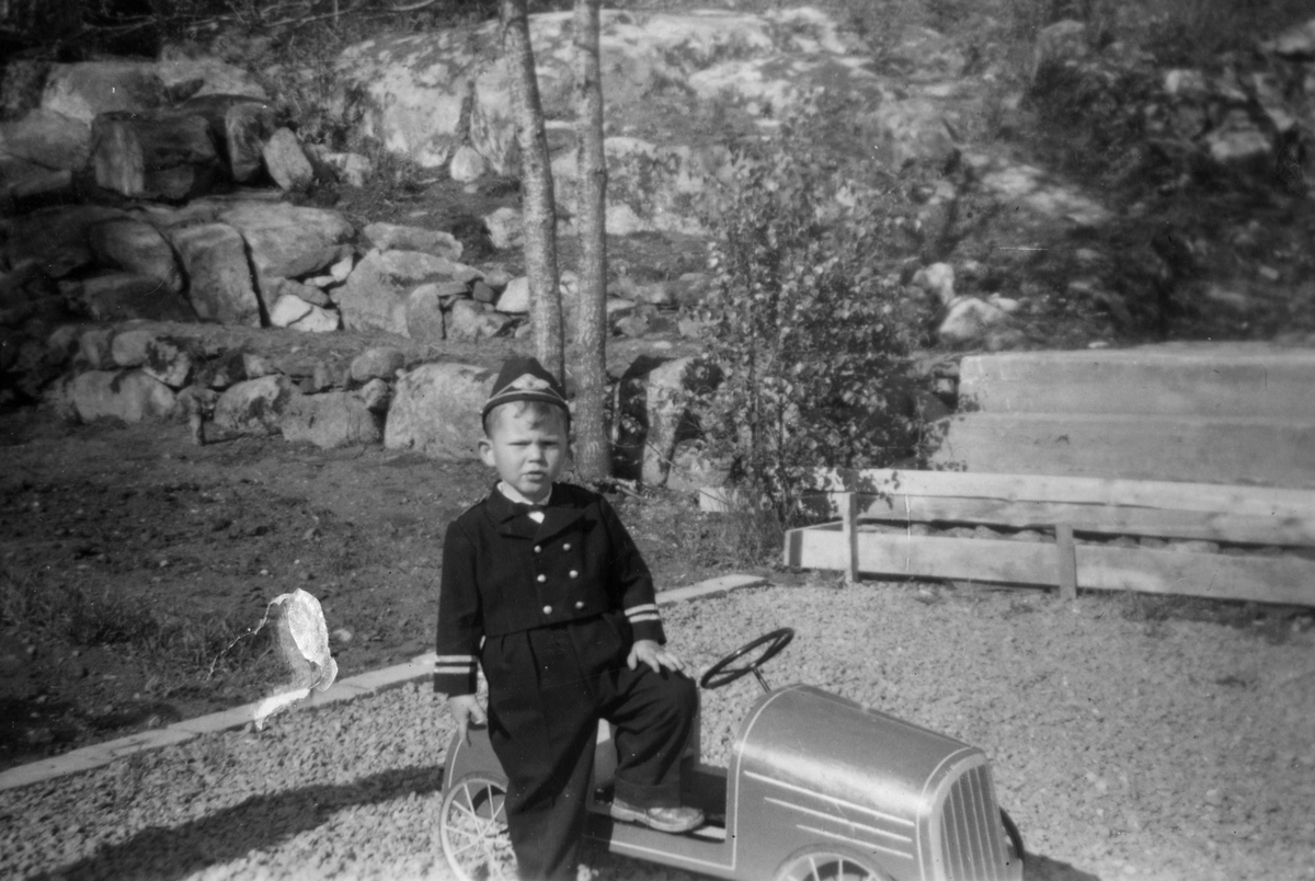 Finn Kreutz med matrosdress fotografert i sin lekebil. 17. mai 1958.