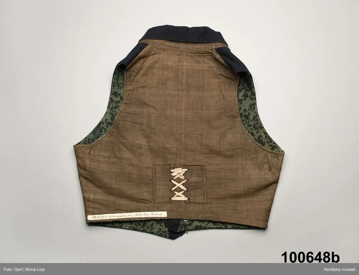 Huvudliggaren (år 1904-1905):
"100.648 a-c Brudgumsdräkt (1830-talet). Tröja, väst och byxor. Av mörkblått kläde. Tröjan och västen fodrade med ylle i grönt och svart, tryckt mönster, byxorna med 'smaik' lucka. Skåne Albo hd Andra-rums sn. Ink. 1904 2/9 Reimer P. L., skollärare, Järstorp, Lövestad. 10:- Bil. Reimer 9"