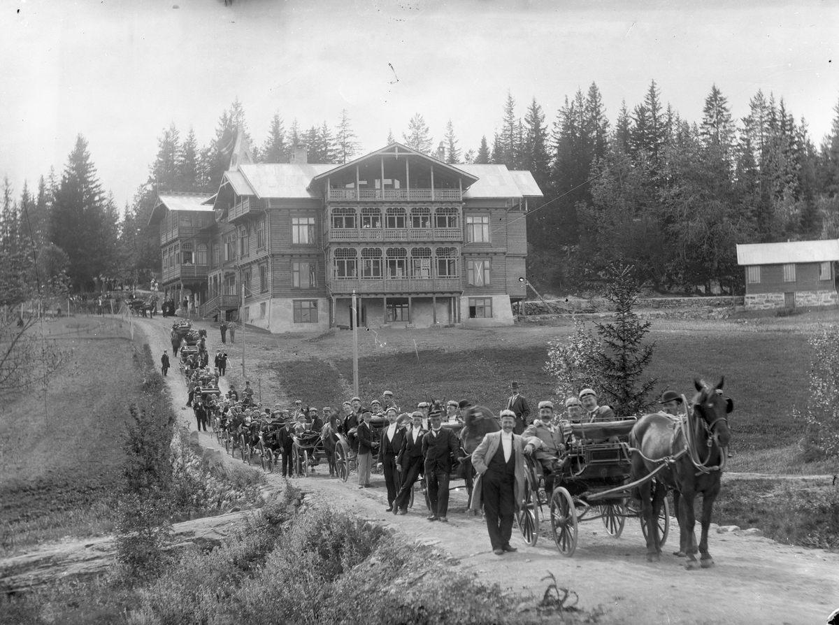 Opptog med hestekjøretøyer på vei foran Konnerudkollen Turisthotell og Sanatorium.