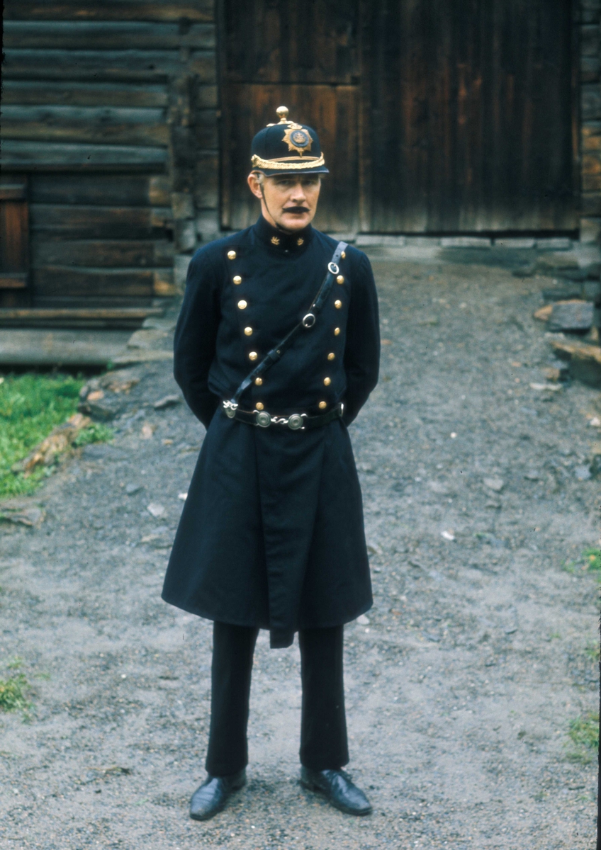 Fra Vognparaden på Norsk Folkemuseum 14.09.1975. Her er en av de ansatte i politiuniform stående i Numedalstunet.