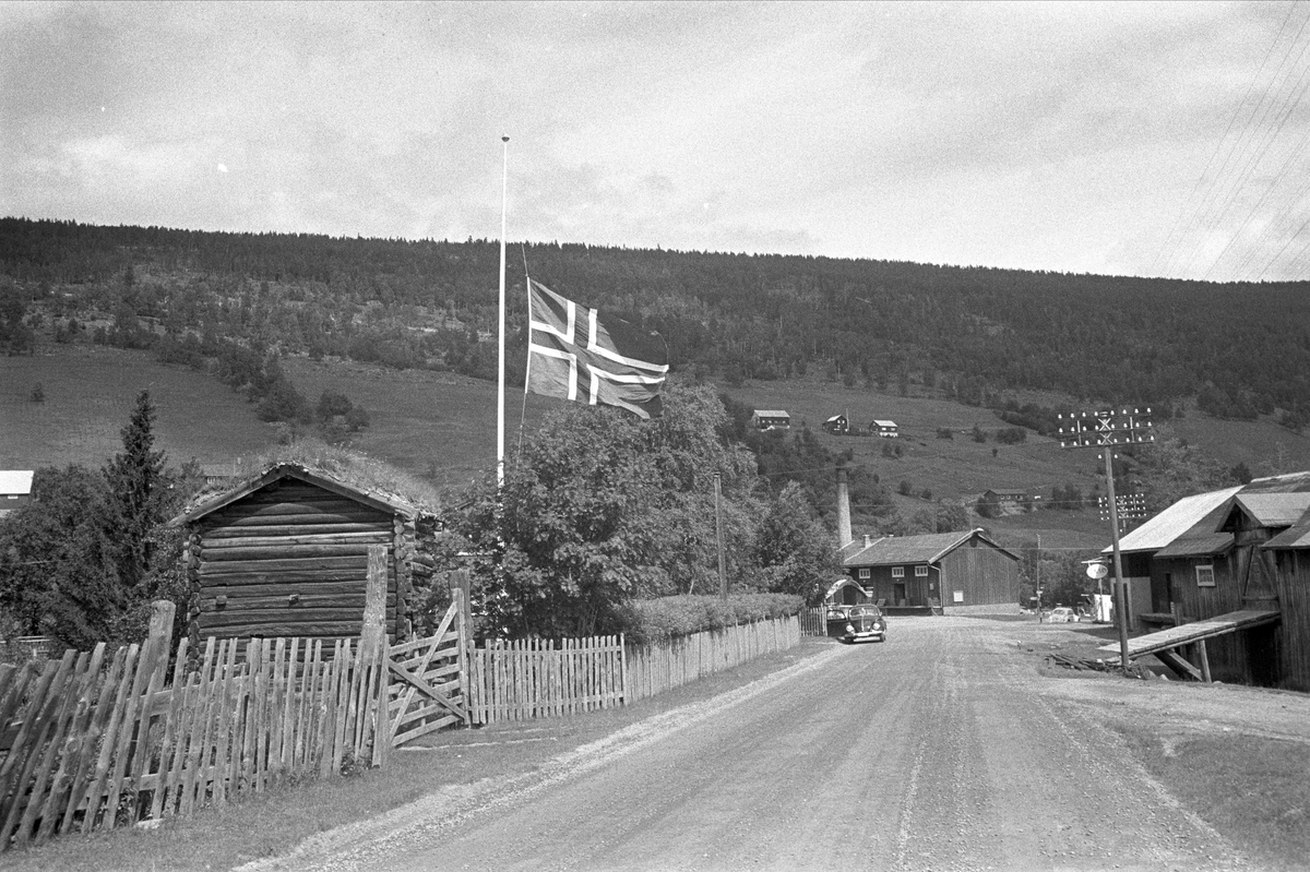 Gudbrandsdalen, juli 1968. Vei, bil og gårder. Flagg på halv stang.