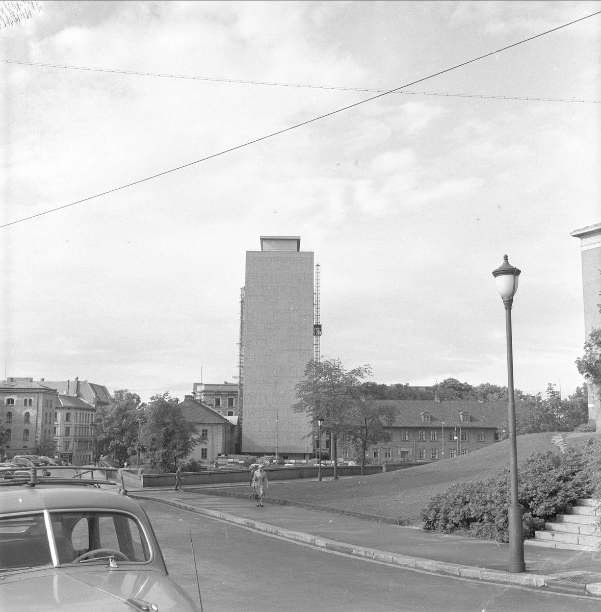 Regjeringsbygget under oppføring mellom gamle bygninger. Til venstre Justisdepartementets bygning i perioden 1883-1958, og til høyre det tidligere Militærhospitalet. Akersgata, Oslo, juli 1958.