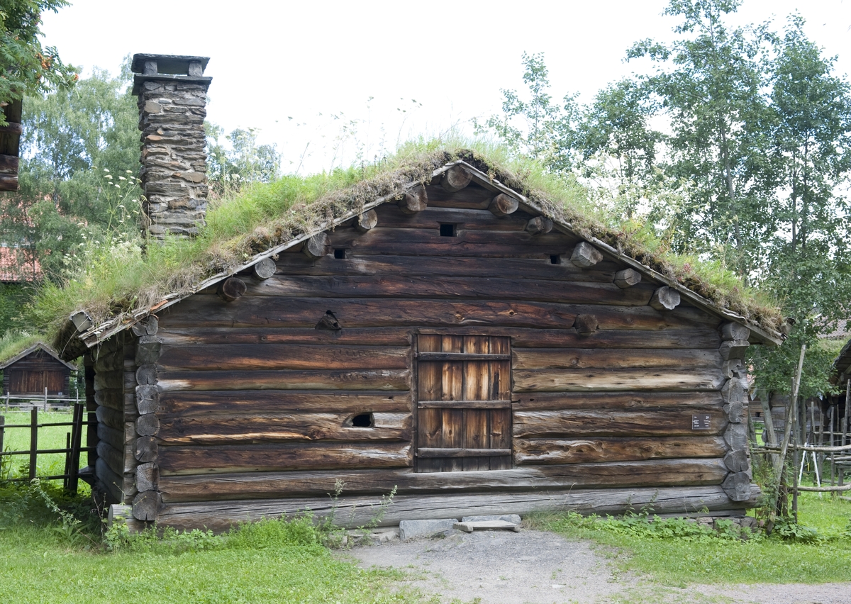 FJØS FRA RAMBERG I HOL, CA. 1800- 1850 
Overført til museet 1942, gjenoppført 1943

Fjøset fra Ramberg i Dagali (nå Hol kommune i Hallingdal) er laftet i én etasje. Innvendig er rommet todelt. To langsgående bjelker gir feste for stolper som deler av båsene. Kyrne sto bundet til ytterveggen. Peisen i hjørnet ved inngangen har innmurt bryggepanne til å koke «sørpe», et slags nødfôr, laget på vann iblandet eksempelvis mose, tørket lauv og oppskavet bark. Grunnmuren under langveggene er like bred som båsene er lange, slik at kyrne sto på muren, på et underlag av torv. Fjøset sto i bratt terreng, og ytterst er grunnmuren derfor høy. Det var åpent rom under fjøsgolvet, som egnet seg til oppbevaring av gjødsel. Møkka ble likevel ikke lagt her, men på tradisjonelt vis kastet ut gjennom en luke i bakveggen, og lagt i en haug utenfor. Senere ble det vanligere å benytte rommet under fjøsgolvet til gjødselkjeller. 

(Tekst hentet fra By og bygd 43, 2010)
