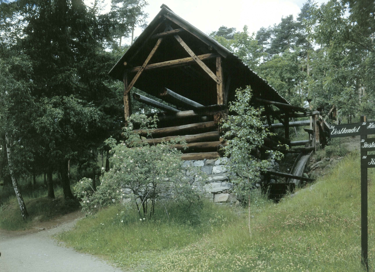 OPPGANGSSAG FRA ÅKRA I ULLENSVANG, 1700-TALLET 
Overført til museet 1932, gjenoppført 1937
 
Saga består av en enkel reisverksbygning med et tømret bolverk under. Den har et stort fast vannhjul som driver saga framover. Et mindre vannhjul, den såkalte «attlaupen», kan løftes opp og ned, og brukes når stokken skal trekkes tilbake igjen. «Vassmerri» kalles det store hjulet som trekker tømmerstokkene opp til saga fra tømmerslepen i fjorden nedenfor. Åkrasaga fikk sitt privilegium i begynnelsen av 1700-årene. Selve bygningen og saginnretningen har gjennomgått en rekke fornyelser, men har likevel beholdt sin opprinnelige karakter. Åkrasaga er en enbladet sag, og har antakelig hatt en kapasitet på tre, fire bord i timen. På slutten av 1700-tallet kom de såkalte silkesagene som hadde flere, opptil åtte parallelle blad. 

(Tekst hentet fra By og bygd 43, 2010)
