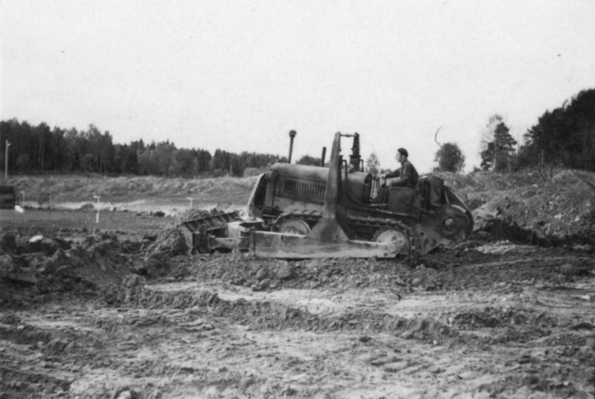 Idrottsplatsen på F 2 Roslagens flygflottilj byggs, 1943. Civilanställda tjänstemän i arbete med grävning. Människor och maskiner i arbete med grävning.