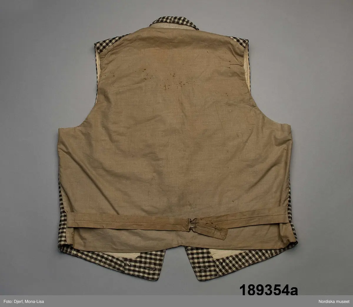 Huvudliggaren (år 1931-1932):
"189354 ab Väst m byxor, från Ösby, Lunda sn, Seminghundra hd, Upland, ylle, smårutigt i svart, grått och vitt; hemspunnet garn och hemvävt tyg, omkr 1860; säljarens svärfaders fästmanskläder; fr. fru Anna Karlsson, Ösby. 25:-"