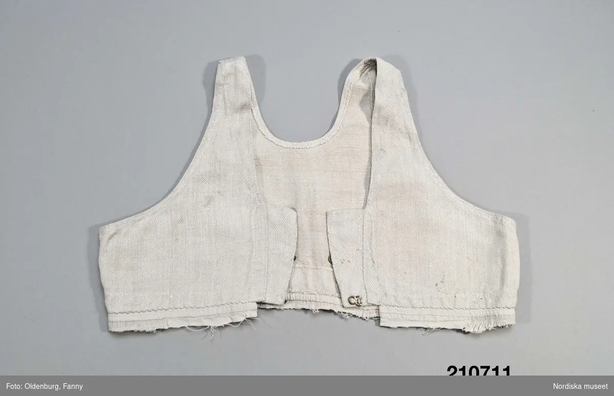 Livstycke, "bod" som varit fastsydd på en linnekjol. Av handspunnet lingarn, blångarn, i treskaftad kypert, "treskäft".  2 raka framstycken och ett ryggstycke, skarvat på axlarna, små kilar i sidsömmarna. Öppet framtill med 3 cm breda knäppkanter på båda sidorna med 2 par hakar och hyskor av mässing. Fåll nedtill med översta delen av kjolen kvar som en ring runtom, där man kan se den täta rynkningen och att kjolen varit av ett tunnare tuskaftat linne.
Denna typ av livkjol kallas i Mora och på Sollerön för vitsärk och användes sommartid. De kunde vävas mer eller mindre grova, och syddes mer eller mindre fint, släta, grovrynkade eller finrynkade och med grövre eller finare liv (bod) alltefter som man avsåg dem till grövsta vardagsbruk eller till helgdagsplagg.
Till fint hade de ofta liv av blommigt tyg men även röda eller gröna vadmalsliv förekom, de enklare hade vitt linneliv med bandgarnering. 
Vitsärkarna kom rätt tidigt ur bruk, sist var det de gamla gummorna, som nyttjade dem. Få är bevarade, ty det var vanligt att kvinnorna sveptes i dem.
Se Ella Odstedt: Folkdräkter i övre Dalarne sid 194-195.

Jfr. hel livkjol från Sollerön inv.nr 211804.
/Berit Eldvik 2007-09-21