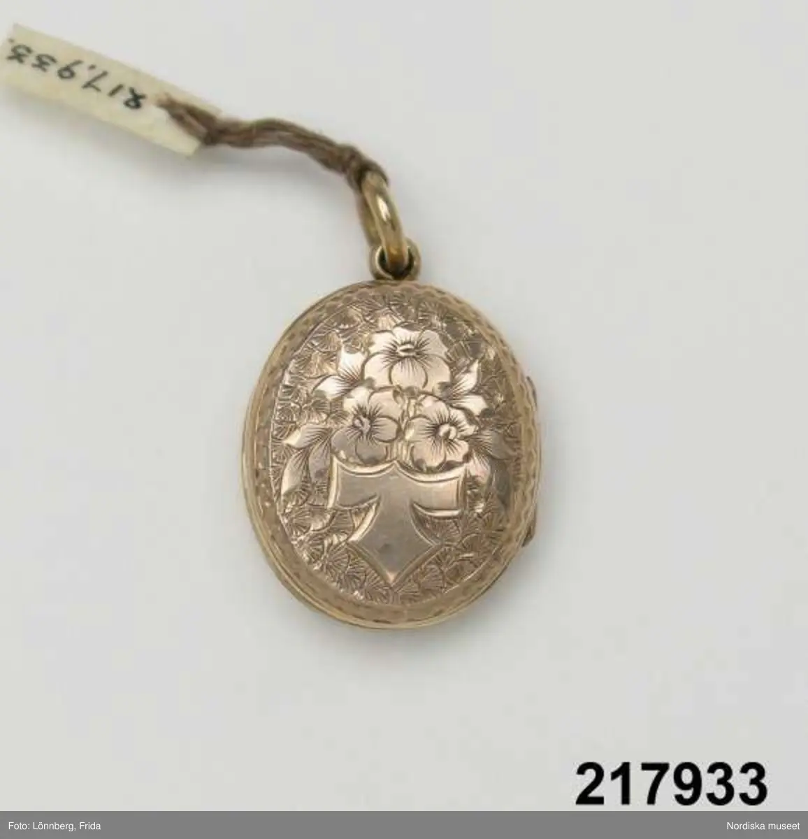 Katalogkort:
"Medaljong, guld med blå emalj,
H. 2,7 cm

Innehåller hårlock."