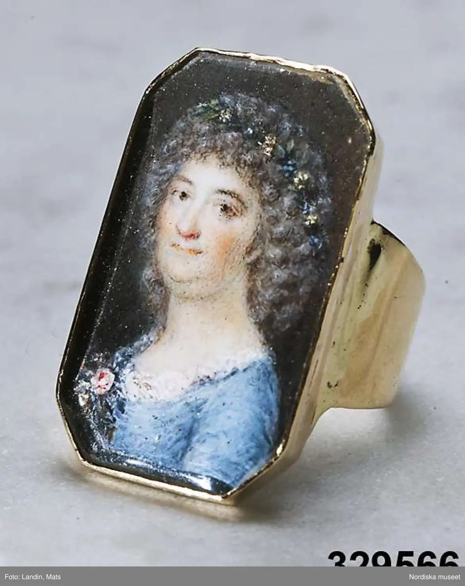  Ring av guld med miniatyrporträtt föreställande Märtha Helena Reenstierna. Målat 1796 på ben i gouacheteknik av Jacob Henric Rönngren (1756-1822) på beställning av M.H.R. även kallad "Årstafrun". Ringen avsedd som gåva till hennnes make ryttmästaren Christian Henric von Schnell på hans namnsdag den 13 november 1796. Graverat C.H.v.S. d. 13 Nov. 1796. 
Monteringen med 18K guld utförd av juveleraren Nils Hofsten. Stämplar: O2 (1796), S:t Erik, NH, 18K,  Kontrollmärke) Sannolikt omarbetad montering 1814.
Porträttet avbildar Märtha Helena Reenstierna i bröstbild sittandes i halvprofil iklädd blå klänning med liten rosenbukett i barmen. Hennes hår är friserat i täta små lockar, håret når nedaför nacken och hon har en smal rosengirlang runt håret. Ögonen bruna. Svagt rosa kinder. Bakgrunden mörk.

Jacob Henric Rönngren var kapten-mecanicus i arméns flotta. Han var född i Finland 1756 men slutade sina dagar i Stockholm 1822. Något dussin av hans miniatyrporträtt är kända - de flesta i Finland och vanligen knutna till officerskåren. Ett porträtt tillhör Finlands Nationalmuseum. I Nationalmuseum, Stockholm, finns sju miniatyrporträtt bl a av gmj Corfitz Beck-Friis (1724-1798), öljt David von Schewen (1770-1841) samt dåv kh i Finska församlingen, Bengt Lange.   

Nils Hofsten blev mästare som juvelerare i Stockholm 1788. Hans ritning till mästerstycke finns på Nationalmuseum. Hofsten stämplade 1795 -1805. Död 1814.
Ingrid Roos 2011-01-17
