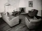 Vardagsrum ed två fåtöljer, en soffa samt en öppen spis i ena hörnet. Nordiska Kompaniet. Arkitekt A. E. Hjort, utställningen Vackra möbler i maj 1937.