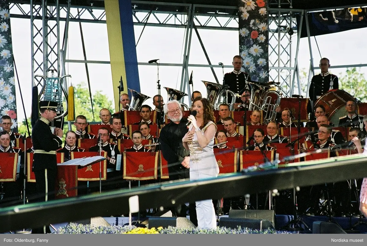 Firandet av den svenska nationaldagen den 6 juni 2004 på Skansen, Stockholm. Den kungliga familjen. Orkester. Publik. Artisterna Jan Malmsjö, Shirley Clamp, Magnus Carlsson.