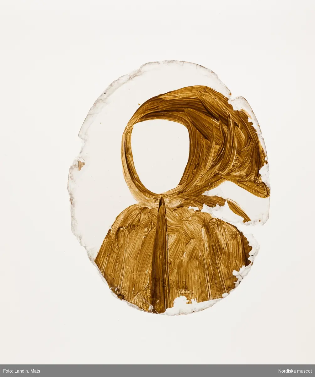 Katalogkort:
"Målning på kopparplåt, osign. Enligt uppgift av givaren föreställande en fröken Hahne. I fodral av svart pressat läder på stomme av papp med 13 glimmerskivor med målade dräkter och dräktdetaljer enligt uppg. målade av prof. N. H. Sjöborg (1767-1838)."
"Blont hår, mörkgrå ögon, rosafärgad klädning besatt med vita spetsar och spetskrage, vitt pärlband i hår och om hals, dessutom juvelhalsband och juvelbrosch. Bakgrund t.h. brunt draperi (vägg?) t.v. träd mot molnig blå himmel, 2 flygande fåglar. Kopparplåten genomborrad upptill. Till detta höra 13 st glimmerskivor att lägga på målningen. I svart ovalt etui, 88 mm x 73 mm av svart refflat skinn, invändigt klätt med ljusblått siden."

Genom att lägga de olika målade glimmerskivorna ovanpå porträttet förändras Kerstin Hahnes utseende. Skivorna visar enligt katalogkort:
- vit turban virad med gulbrunt, ljusbrun draperad dräkt med svarta prickar
- svart huvudbonad och gula örhängen
- svart huvudbonad, ljusröda örhängen, ljusröd bröstrosett
- svart hatt, svart kort jacka, vit krage och vita ärmar synliga i uppslitsningarna
- svart dok och klädning, vit krage
- ljusröd hårprydnad, örhängen vita och ljusröda, svart klädning med vit krage
- ljusbrunt hårnät, dito örhängen med vita pärlor, ljusbrun klädning med vita ärmar
- vitt nunnedok, svart dräkt
- ljusbrun hårprydnad, möjligen nät av band, vita örhängen, svart klädning, vit krage
- brun huva med krage, möjligen kappa
- svart barett med en grön, en vit och en rosafärgad plym, fästade med en gul agraff, vita örhängen, vit bröstrosett
- hårklädsel av 3 gula fjädrar samt en gul, en vit, och en grön plym, svart mask, vita örhängen, vitt band som täcker hakan, två gula bröstrosetter
- hårprydnad (nät?) ljusrött, röd och vita örhängen, till venster en neger, som omfamnar damen, under negerns huvud något gulvitt, som möjligen tillhör hans dräkt

Kerstin Hahne, död 1656, gift med Honorat Verdelet, var dotter till uppvaktaren hos kung Karl IX:s barn, Christoffer Hahne till Hesselby och Ingrid Björnsdotter.