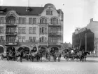 Brandkåren. Fyra av brandkårens vagnar, med brandsoldater, på Stortorget framför Karlmarkska palatset.       Bild från sekelskiftet. Karlmarkska palatset byggdes 1905 och var det första huset i stan som hade el, värme och rinnande vatten. Det revs 1976 för att ge plats för köpcentrat Valen.