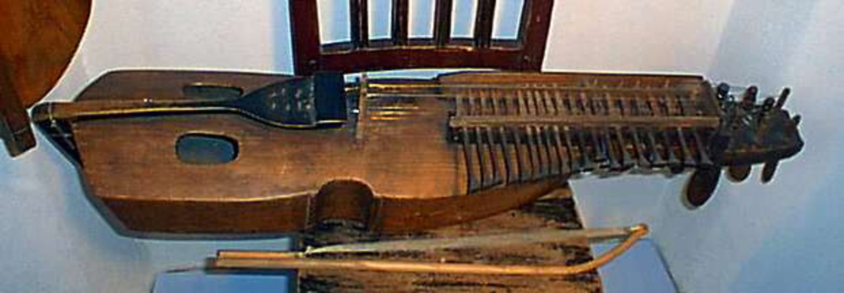 Nyckelharpa, s.k. kontrabasharpa. Korpus bestående av skrov täljt av granträ med lock i granträ. Nyckellåda av lövträ. Nyckellådans överliggare dels intappad dels fastskruvad med järnskruv. Dubbla nyckelrader med i övre raden 19 nycklar och i den undre två. Harpan har tre melodisträngar och ev. bordunsträng. Stränghållare av svartmålat lövträ fastbunden med snöre. Stämskruvar och nycklar av svartmålat lövträ.