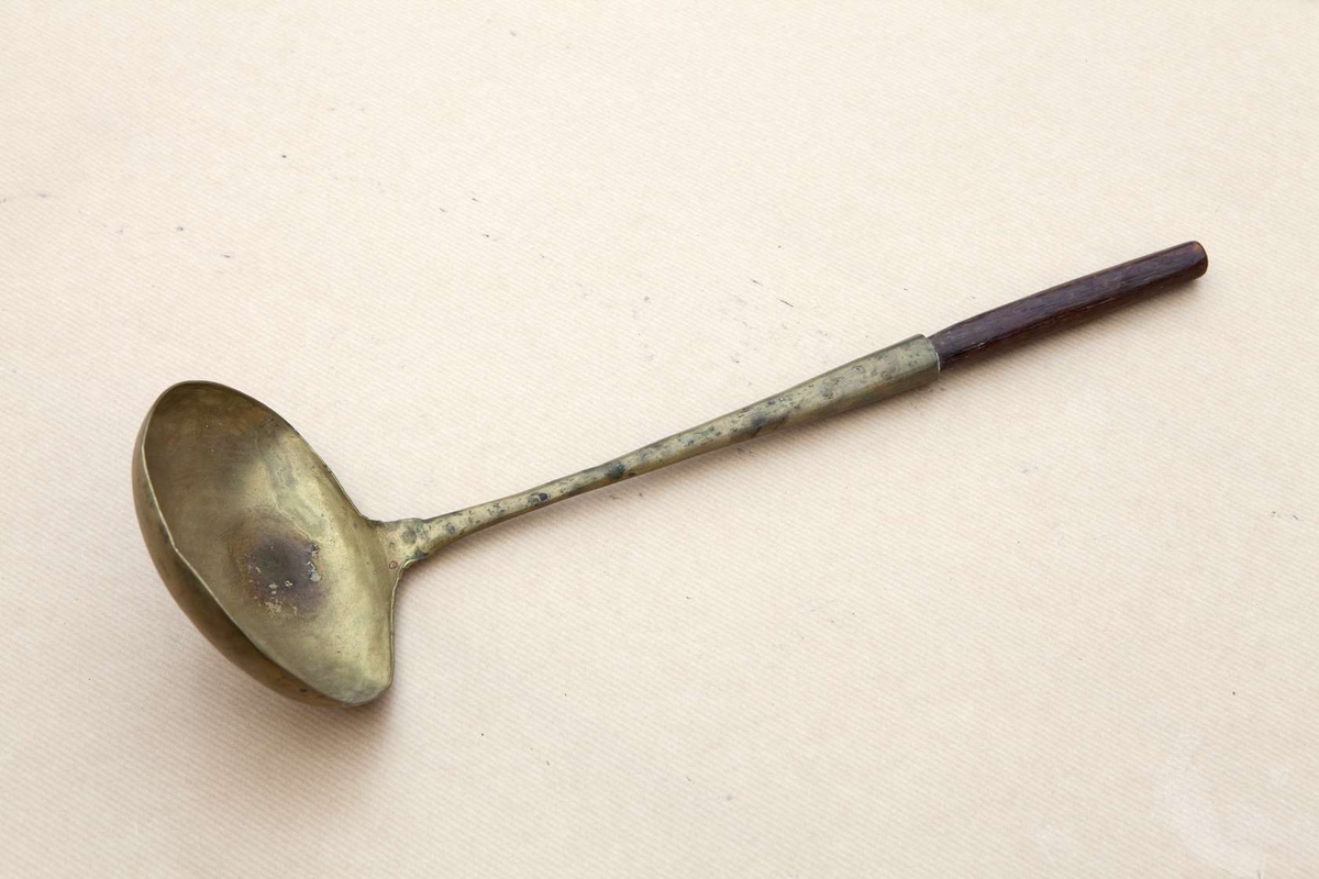 Slev av mässing med järn i skaftet. Ytterdelen av skaftet av trä.