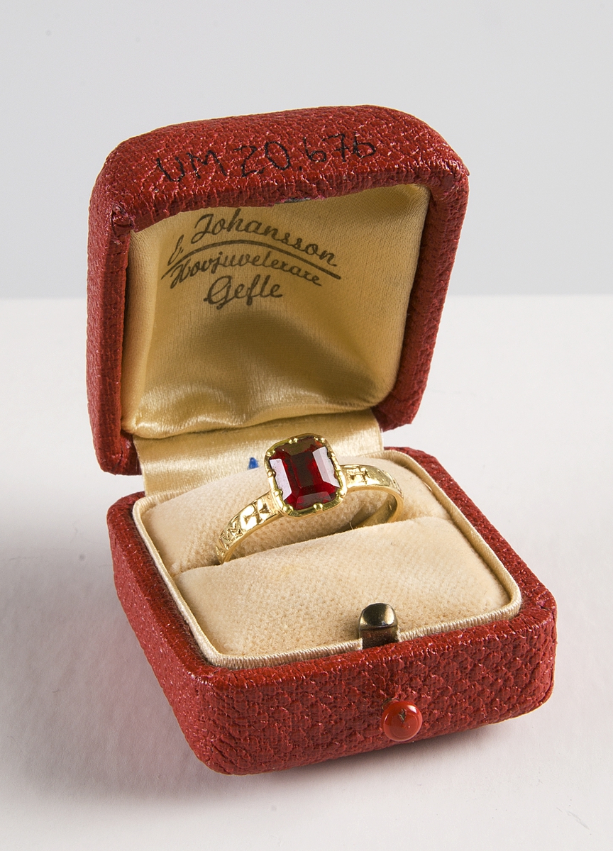 Fingerring av guld med infattad röd sten och handslag på skenans baksida. På ringens utsida ingraverat  AVEM ARIA ( d.v.s. AVE MARIA) och två likarmade kors. Tillhörande etui UM20676b.

Didners lät sätta in den ljusröda rubinen.