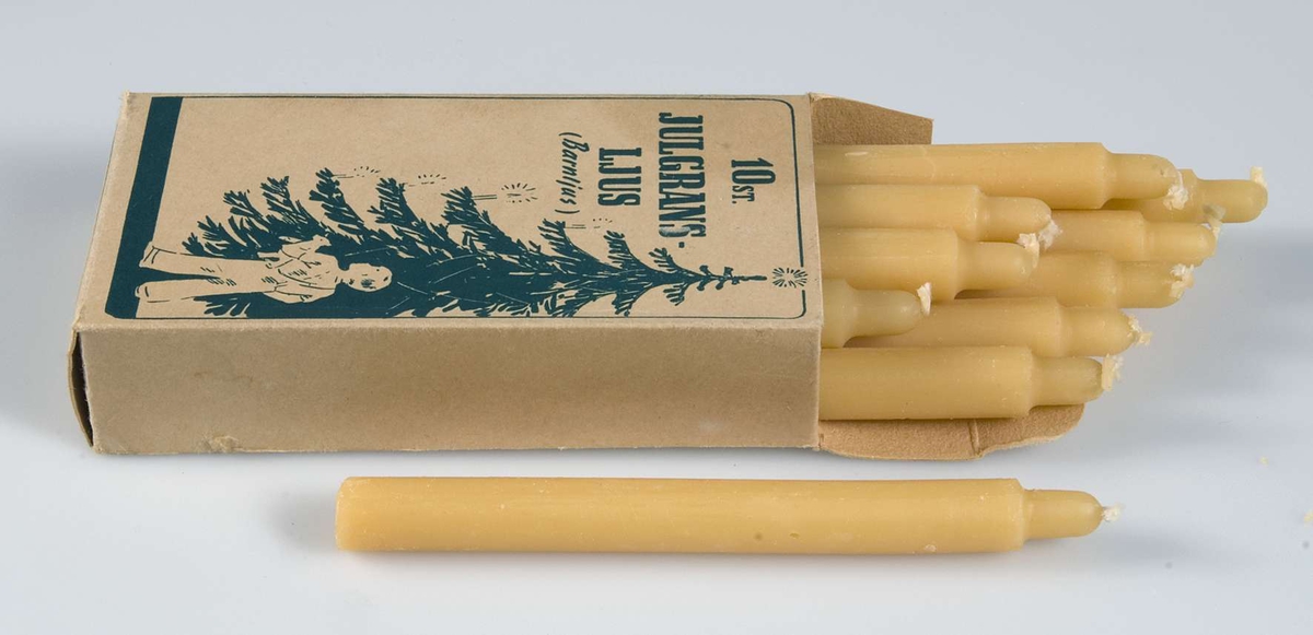 Två kartonger av brunbeige papp med grönt tryck, bild av julgran och ett barn och text: 10 st JULGRANSLJUS, (Barnljus), Tekniska Fabriken Elky, Stockholm. Innehåller 10 gulvita stearinljus. 