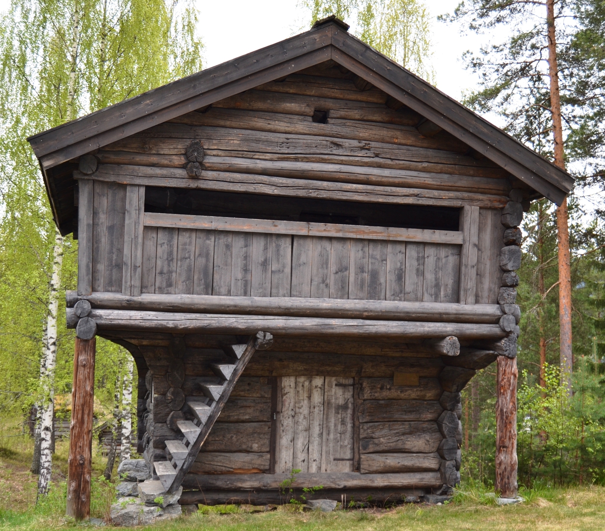 Tømret loft med åpen utkraget svalgang i andre etasje på to av kortsidene og den ene langsiden.