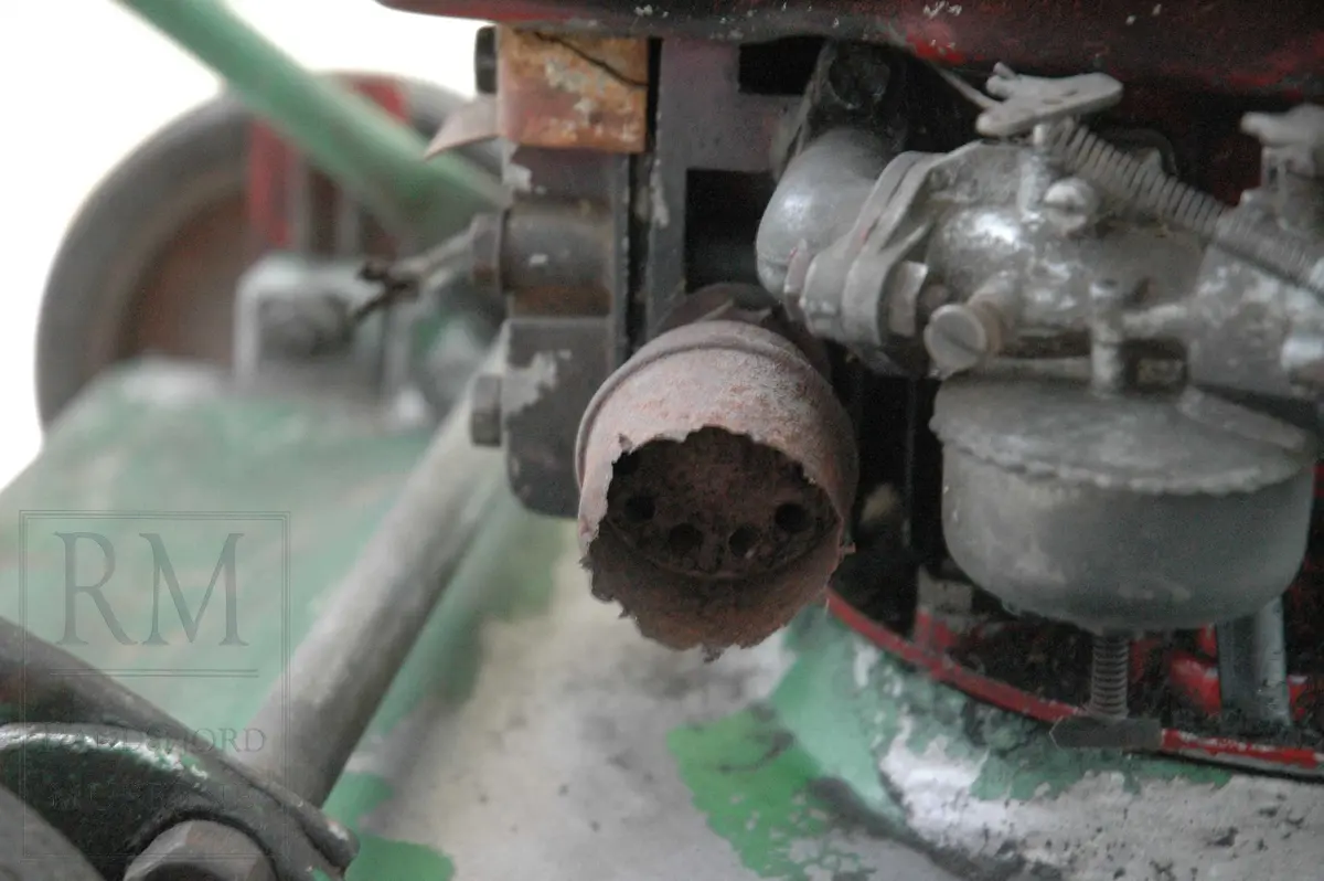 Gressklipper i aluminium med 4 gummihjul. Motor midt på. Motor har boks festet på siden. Metallhåndtak. Gresset blåses ut til høyre.