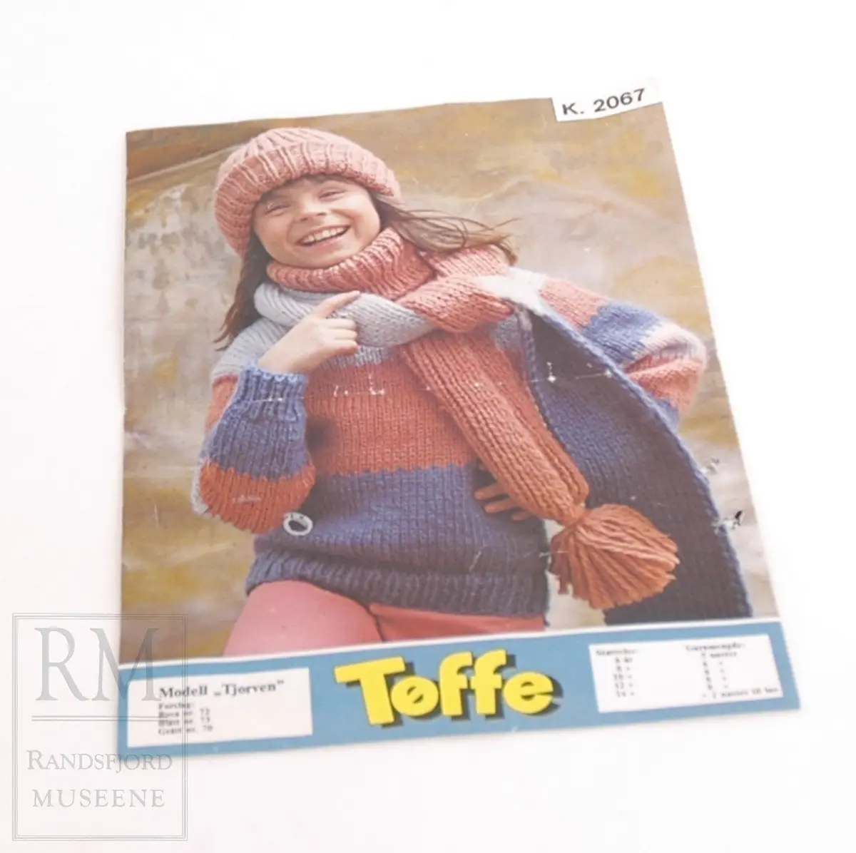  A4 ark brettet i to med foto på fremsiden og oppskrift inni og bak på arket
Modell "Tjorven"
Jente med strikket genser, lue og skjerf i lilla og rosa.
